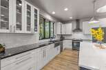 Experience modern living in this stunning kitchen featuring sleek white cabinetry, elegant black countertops, and a beautiful subway tile backsplash.