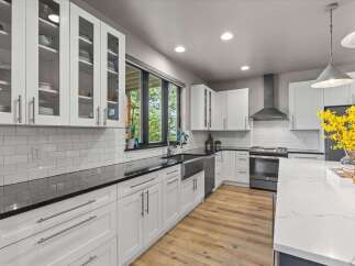 Experience modern living in this stunning kitchen featuring sleek white cabinetry, elegant black countertops, and a beautiful subway tile backsplash.