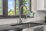 Experience modern kitchen luxury with this stunning farmhouse sink and sleek faucet.