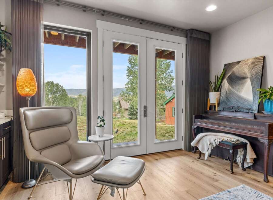 Experience breathtaking mountain views from this stunning living space, featuring a comfortable armchair and ottoman perfect for relaxation.