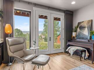 Experience breathtaking mountain views from this stunning living space, featuring a comfortable armchair and ottoman perfect for relaxation.