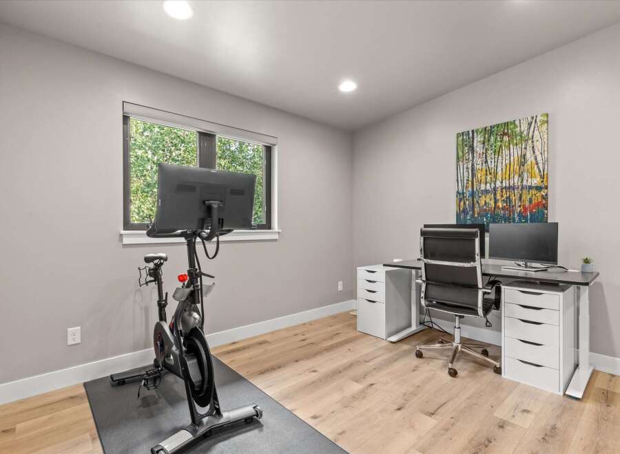 This modern home office features a Peloton bike for your workouts and a spacious desk with dual monitors for productivity.
