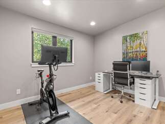 This modern home office features a Peloton bike for your workouts and a spacious desk with dual monitors for productivity.