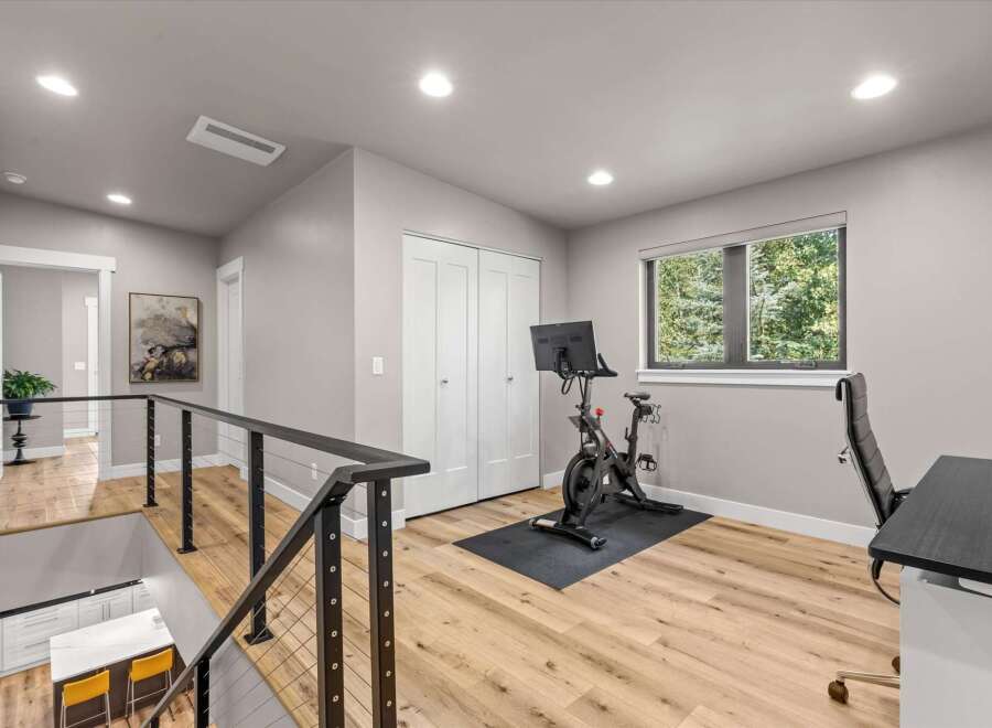 This modern home features a dedicated home gym space with a Peloton bike and a comfortable office chair, perfect for staying active and productive.