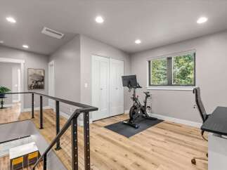 This modern home features a dedicated home gym space with a Peloton bike and a comfortable office chair, perfect for staying active and productive.