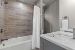 Experience modern comfort in this beautifully appointed bathroom, featuring elegant wood-look tile shower walls and a sleek white bathtub.
