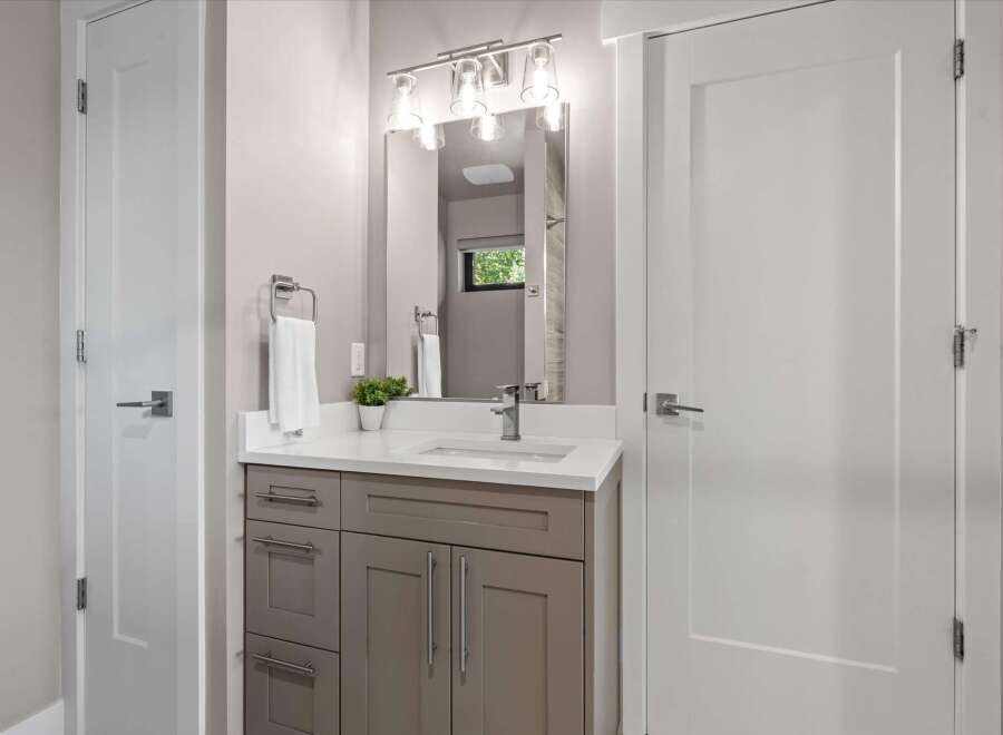 This modern bathroom features a sleek vanity with ample storage and a clean white countertop.