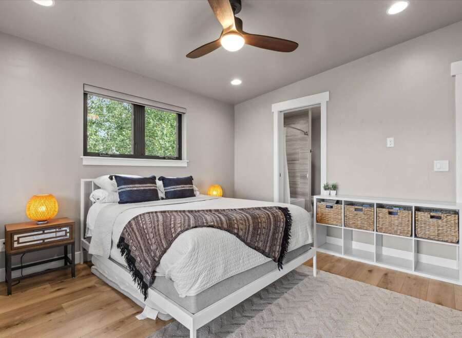 Discover comfort and style in this inviting bedroom, featuring a plush bed adorned with decorative pillows and a cozy throw blanket.