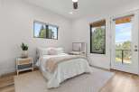 Experience modern comfort in this bright bedroom featuring a plush white bed adorned with a cozy knit throw and decorative pillows.