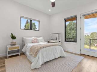 Experience modern comfort in this bright bedroom featuring a plush white bed adorned with a cozy knit throw and decorative pillows.