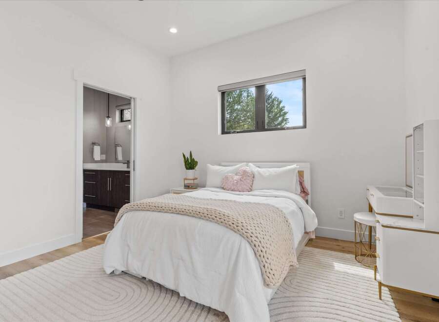 This bright and airy bedroom features a comfortable queen-size bed with crisp white linens and a plush knit throw.
