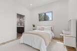 This bright and airy bedroom features a comfortable queen-size bed with crisp white linens and a plush knit throw.