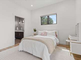 This bright and airy bedroom features a comfortable queen-size bed with crisp white linens and a plush knit throw.