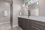 Experience modern luxury in this stunning bathroom featuring a sleek vanity with ample storage and a spacious glass-enclosed shower.
