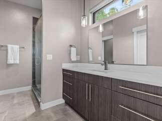 Experience modern luxury in this stunning bathroom featuring a sleek vanity with ample storage and a spacious glass-enclosed shower.