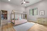 This charming children's bedroom features a whimsical house-shaped bed with a pink comforter and plush pillows, creating a cozy and inviting sleep space.