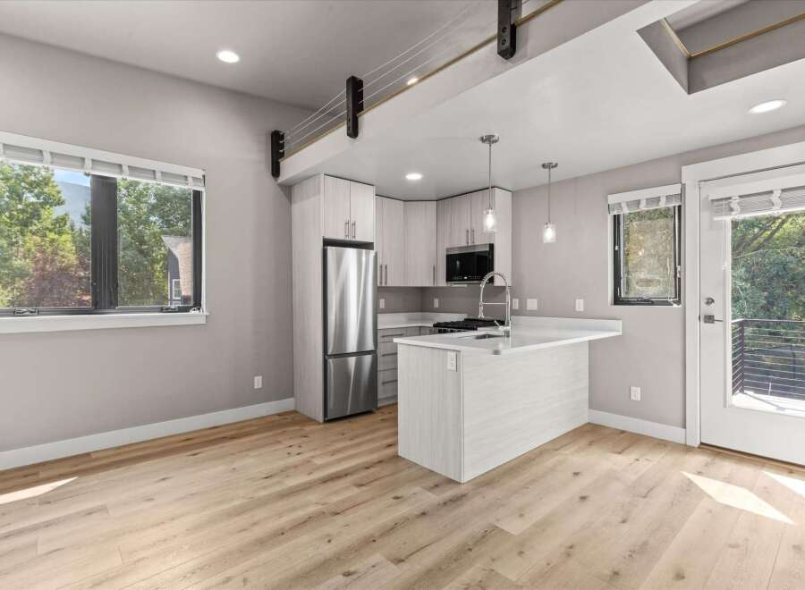 Experience modern living in this stylish apartment featuring a sleek, open-concept kitchen with a central island and stainless steel appliances.