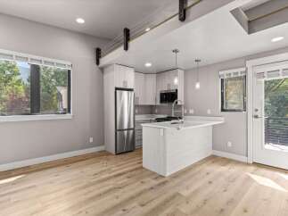Experience modern living in this stylish apartment featuring a sleek, open-concept kitchen with a central island and stainless steel appliances.