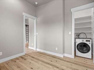 Discover modern convenience in this home featuring a dedicated laundry closet equipped with a sleek, front-loading washing machine.