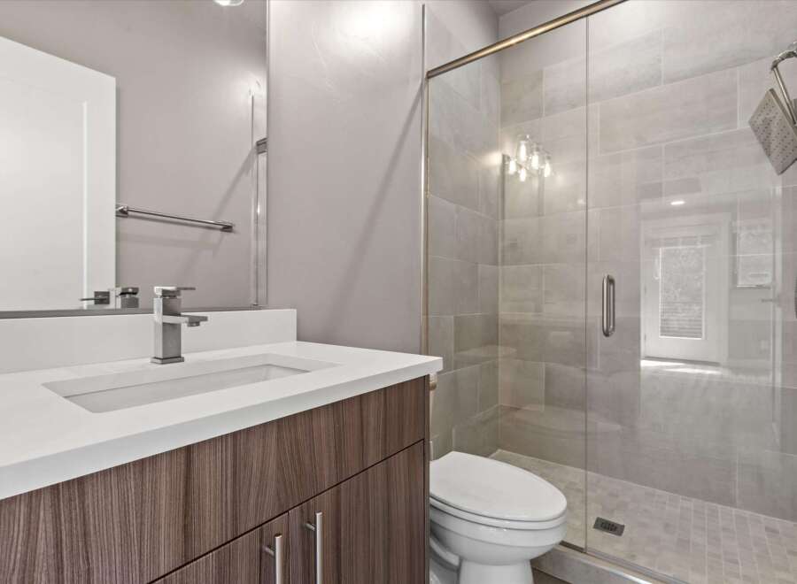 Experience modern luxury in this stunning bathroom featuring a sleek vanity with a white countertop and a stylish faucet.