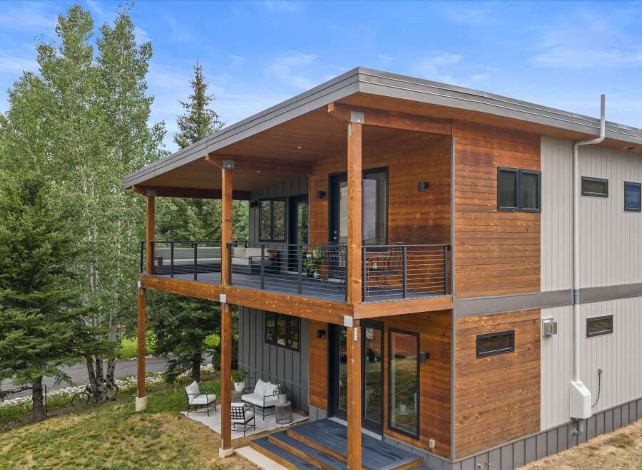 Experience modern living in this stunning multi-level home, featuring a striking combination of warm wood siding and sleek gray panels.