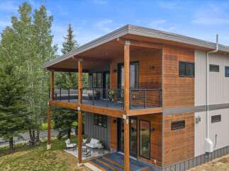 Experience modern living in this stunning multi-level home, featuring a striking combination of warm wood siding and sleek gray panels.