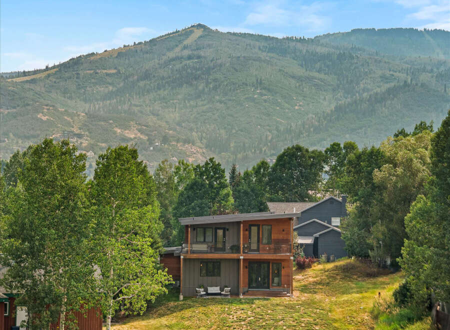 Experience modern mountain living in this stunning home, featuring a striking contemporary design with warm wood accents and expansive windows.