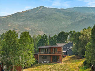 Experience modern mountain living in this stunning home, featuring a striking contemporary design with warm wood accents and expansive windows.