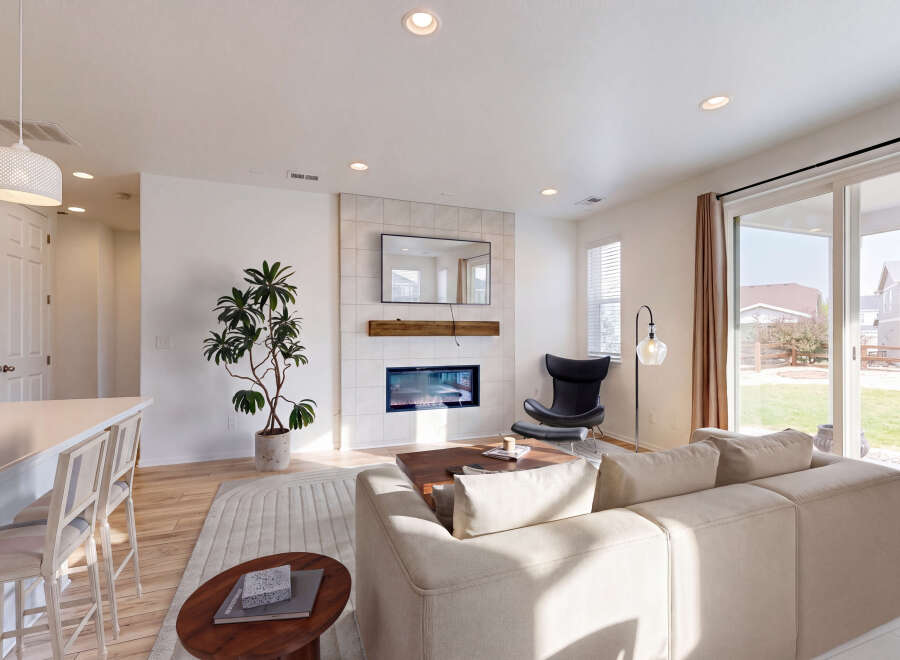 Experience modern living in this spacious great room, featuring a sleek fireplace with a tiled surround and a mounted television.