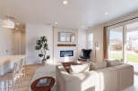 Experience modern living in this spacious great room, featuring a sleek fireplace with a tiled surround and a mounted television.