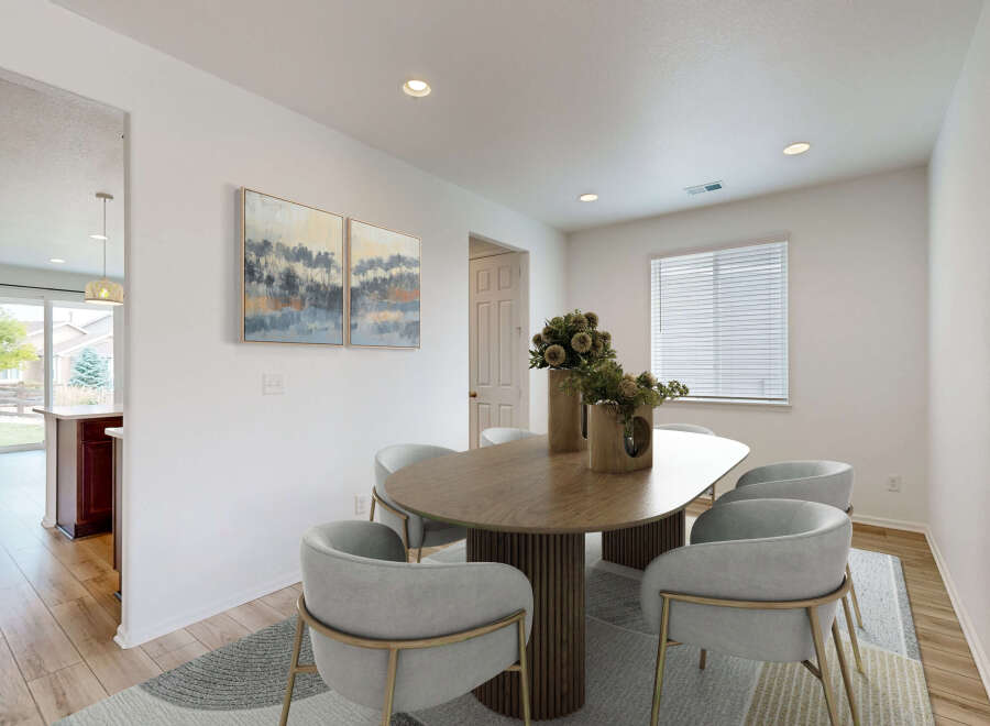 This dining room features a modern oval dining table with a fluted base, surrounded by stylish grey upholstered chairs with gold accents.
