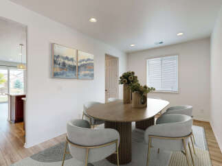 This dining room features a modern oval dining table with a fluted base, surrounded by stylish grey upholstered chairs with gold accents.