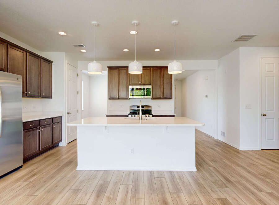 This spacious kitchen boasts modern stainless steel appliances, including a refrigerator and a gas range.