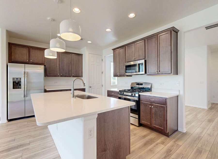 Experience modern living in this stunning kitchen featuring a spacious island with a built-in sink and elegant pendant lighting.