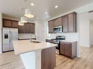 Experience modern living in this stunning kitchen featuring a spacious island with a built-in sink and elegant pendant lighting.