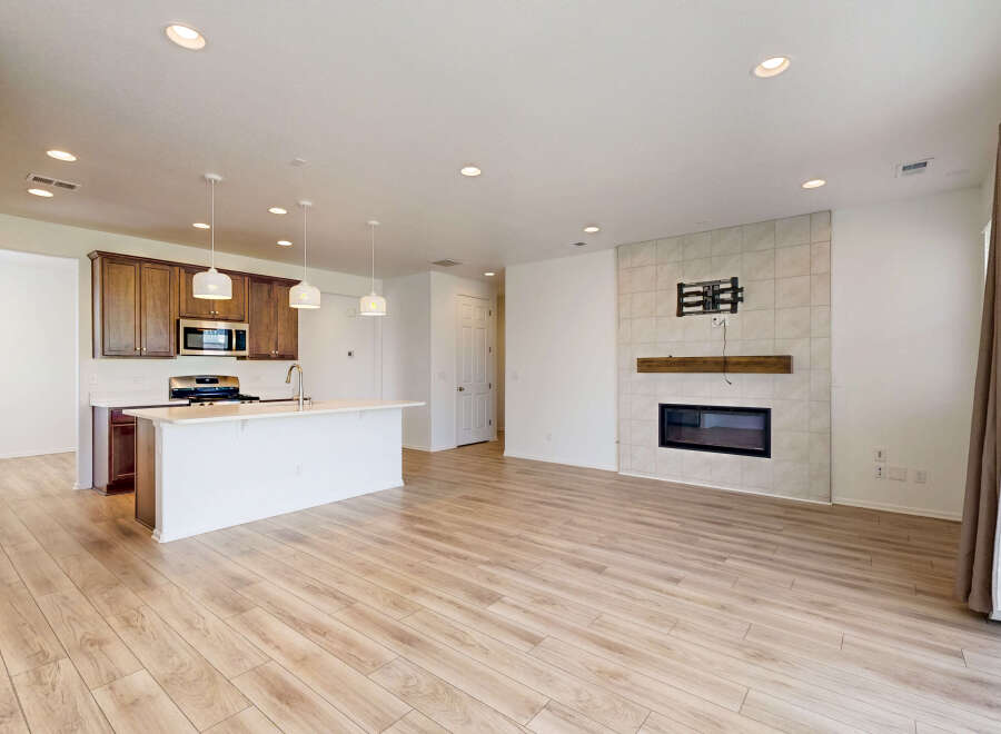 Experience modern living in this open-concept home featuring a sleek kitchen with rich wood cabinetry and a spacious island.