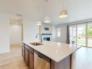 Experience modern living in this stunning open-concept home, featuring a sleek kitchen island with a built-in sink and dishwasher.