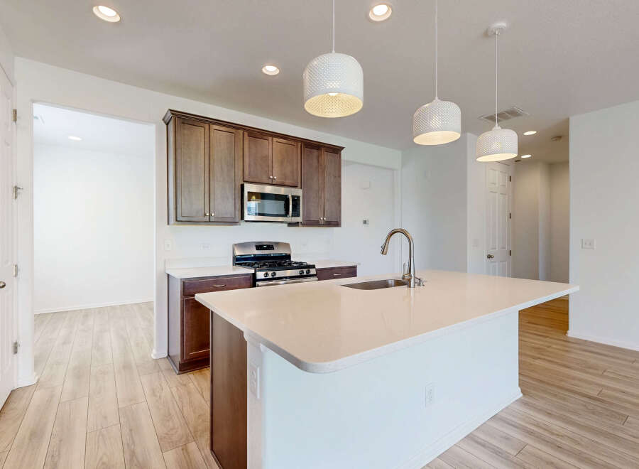 Experience modern living in this stunning kitchen featuring a spacious island with a sleek faucet and sink.