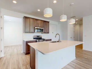 Experience modern living in this stunning kitchen featuring a spacious island with a sleek faucet and sink.