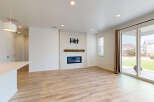 Experience modern living in this spacious great room featuring a sleek fireplace with a tiled surround and a rustic wooden mantel.