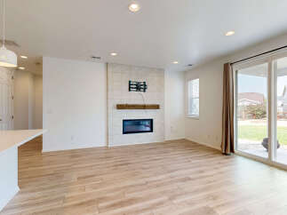 Experience modern living in this spacious great room featuring a sleek fireplace with a tiled surround and a rustic wooden mantel.