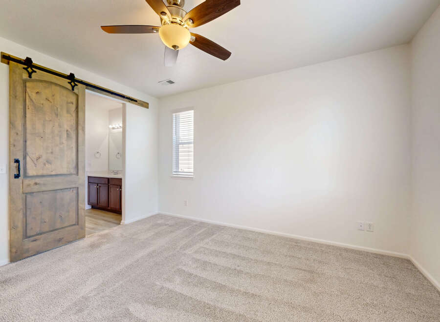Step into this inviting bedroom featuring a stylish barn door that opens to an ensuite bathroom.