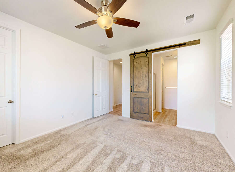 Step into this inviting bedroom featuring a rustic barn door leading to an ensuite bathroom.
