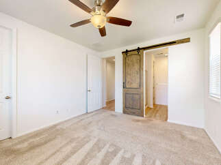 Step into this inviting bedroom featuring a rustic barn door leading to an ensuite bathroom.