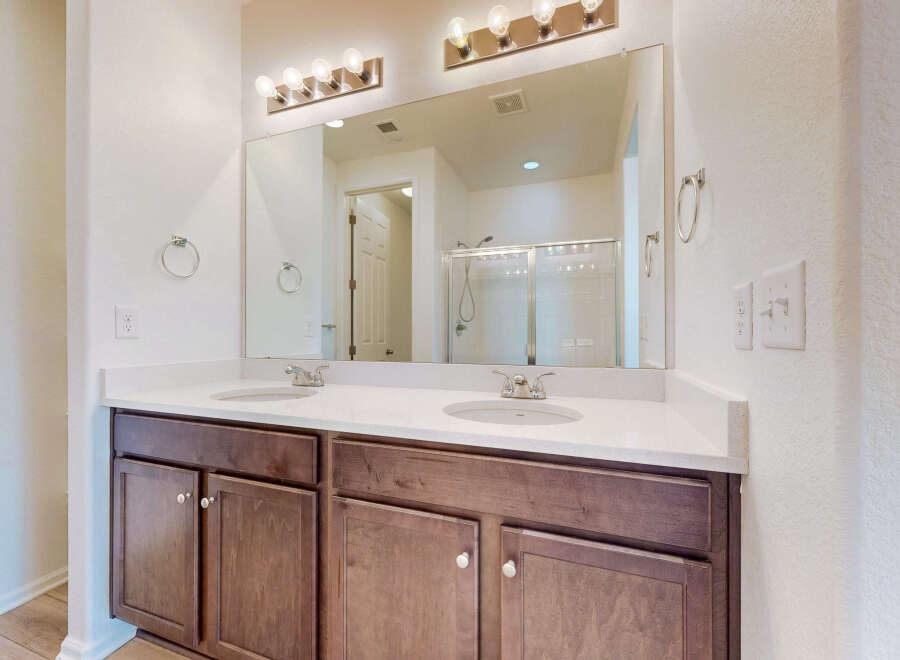 This modern bathroom features a spacious double vanity with a white quartz countertop and dark wood cabinetry.