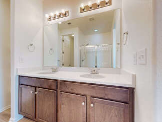 This modern bathroom features a spacious double vanity with a white quartz countertop and dark wood cabinetry.