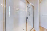 Step into this pristine white tiled shower, featuring a sleek glass enclosure and a modern chrome showerhead.