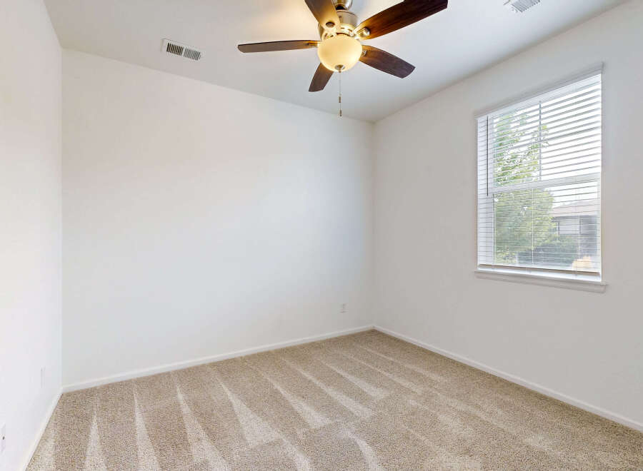 This empty bedroom features neutral beige carpeting and clean white walls, creating a blank canvas for your personal style.