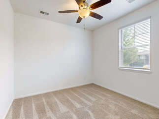 This empty bedroom features neutral beige carpeting and clean white walls, creating a blank canvas for your personal style.