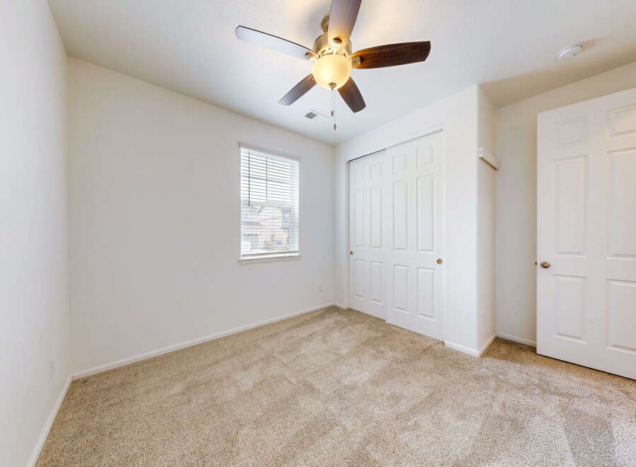 Step into this inviting bedroom featuring a plush carpeted floor and a convenient ceiling fan for year-round comfort.